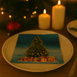 Juleserviett med motiv av juletre og gaver, plassert på en hvit tallerken på et oppdekket julebord med tente lys.
