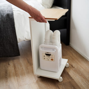 Hvit bord med hjul og lys treplate, perfekt som nattbord eller ved sofaen.