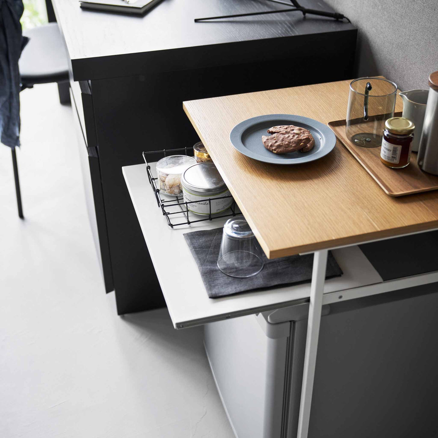 Sidebord med uttrekkbar hylle brukt som lite skrivebord med laptop og kaffekopp