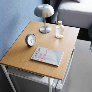 Kompakt sidebord med treplate brukt som nattbord med lampe og bok