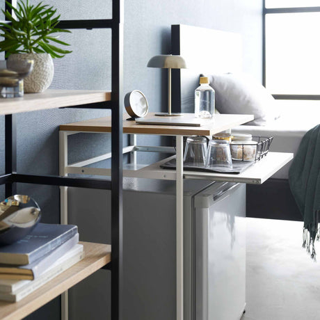 Detaljbilde av uttrekkbar hylle på sidebord med hvit stålramme