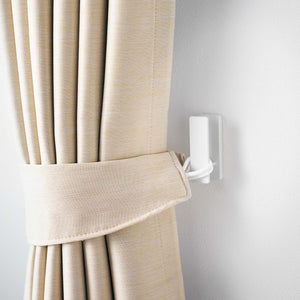 Nærbilde av hvit metallkrok festet med skrue i lys vegg.