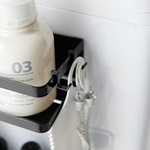 Magnetisk oppbevaringshylle på vaskemaskin med flasker og håndklær.