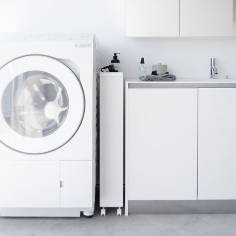 Smal hvit hyllevogn med oppbevaring av flasker og vaskemidler.