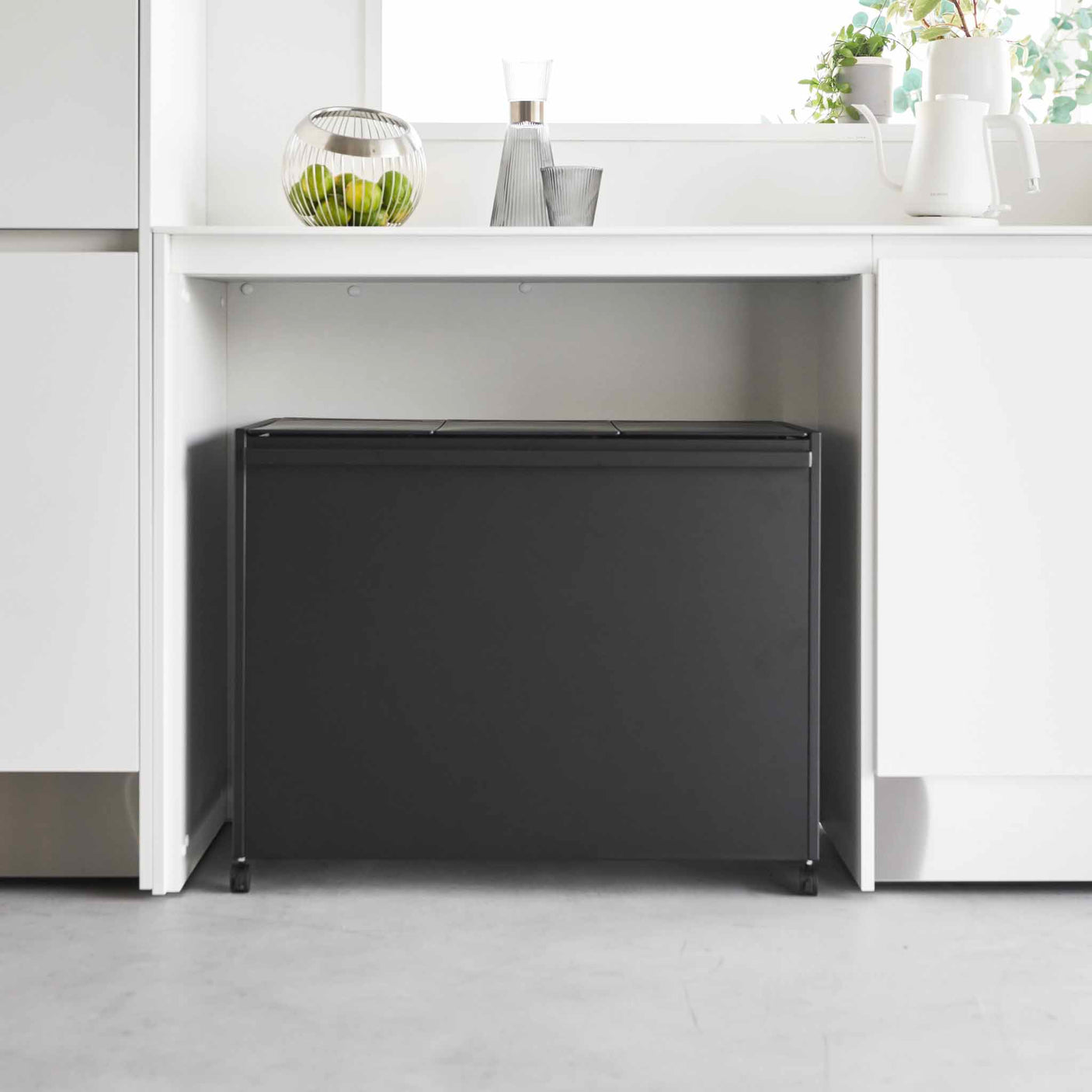 Kildesorteringssystem med hjul plassert under kjøkkenbenk i moderne kjøkken