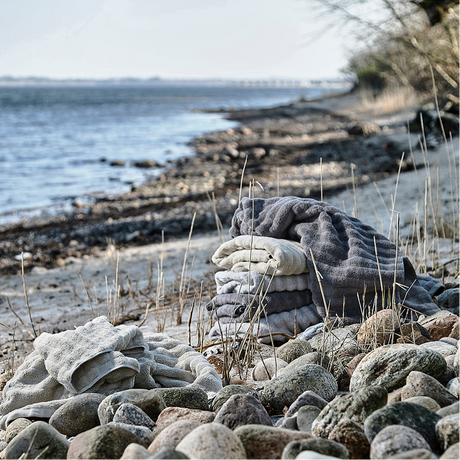 Mykt håndkle i dempet grå farge brettet på bad