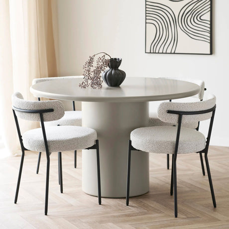 Moderne rundt spisebord i beige med fire bouclé-stoler og sort vase – stilrent interiør for nordiske hjem med minimalistisk preg.