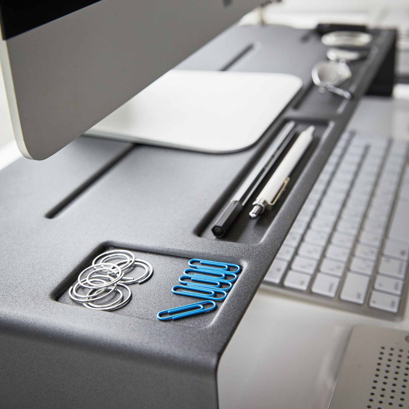 Detaljbilde av oppbevaringsspor på sort monitorstativ