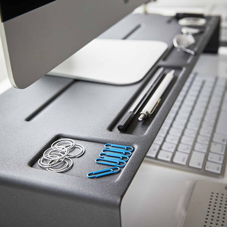 Detaljbilde av oppbevaringsspor på sort monitorstativ