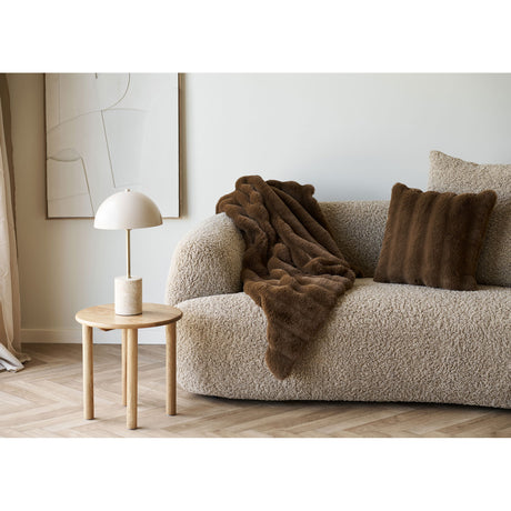 Brun Galena pute i kunstpels plassert i sofa sammen med matchende pledd