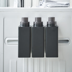 Person fyller opp sort magnetisk flaske med oppvaskmiddel.