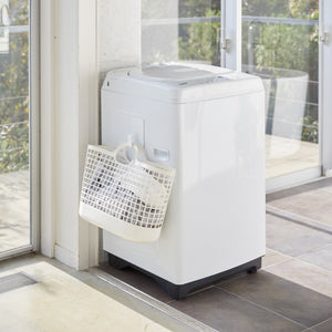 Hvit krok med magnetfeste holder skittentøyskurv på plass.