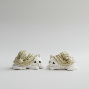 To små kattefigurer i polyresin med grønne luer på hvit bakgrunn