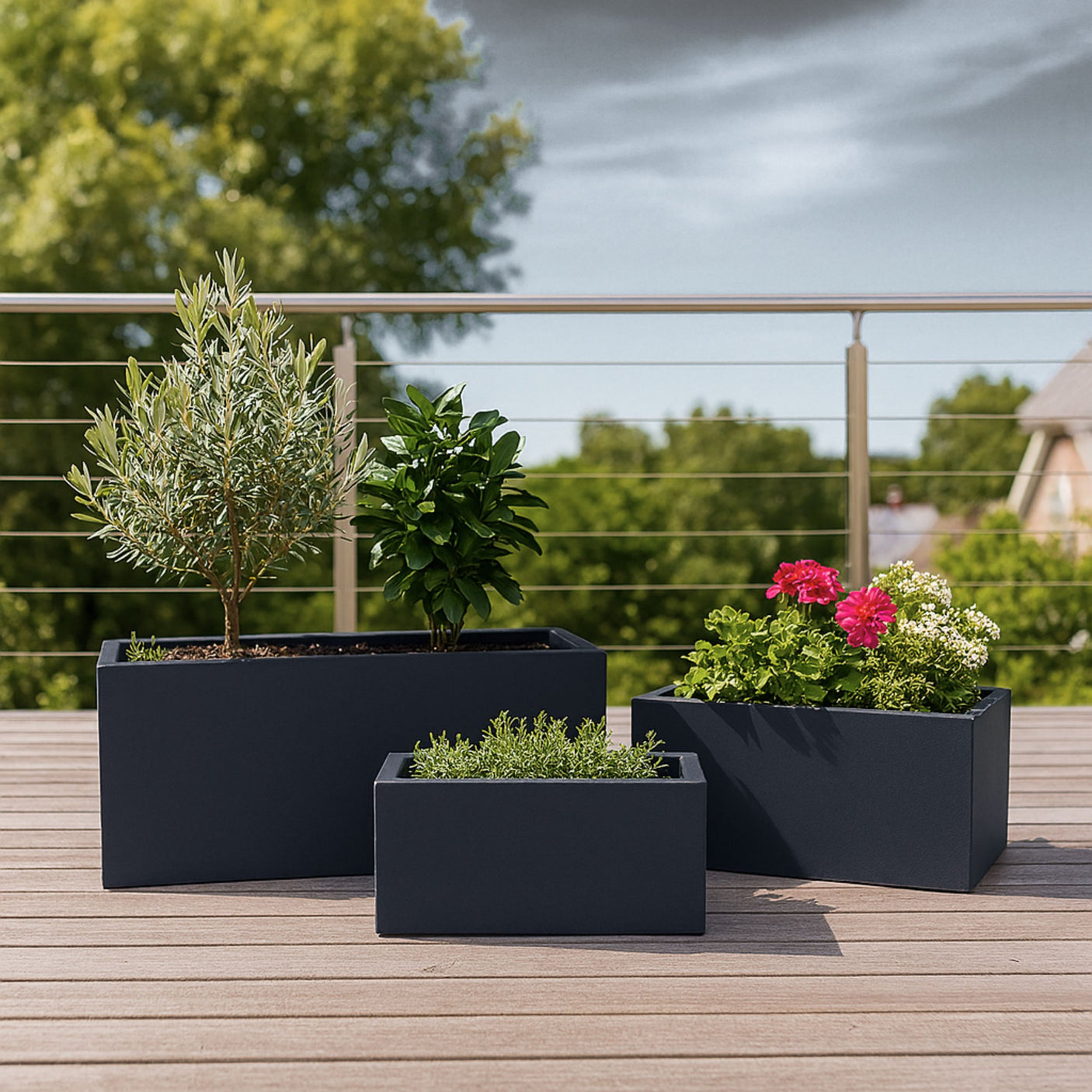 Moderne terrasse med tre svarte blomsterkasser fylt med urter, blomster og små trær – perfekt for stilfull dyrking på balkong eller platting