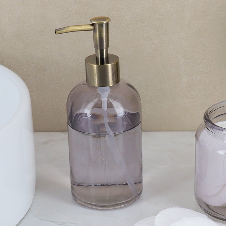 Glas-tvåldispenser sett från sidan med bronsfärgad pump.