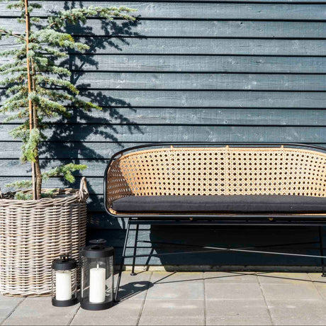 Sorte lanterner ved rottingsofa utendørs