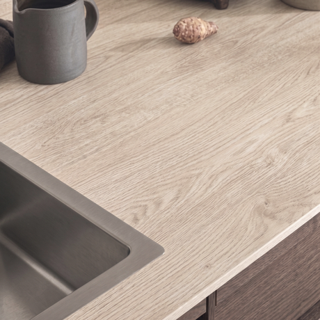 Nærbilde av kjøkkenbenk med Blond Oak kontaktplast rundt vasken, lys eikestruktur med årer