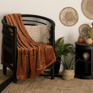 Rustbrunt fleecepledd drapert over svart stol i lun stue