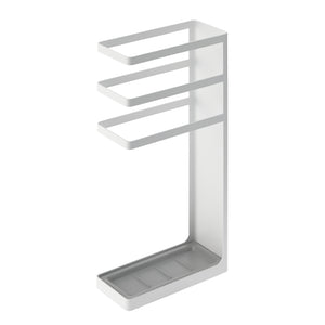Paraply i svart metallstativ med dryppskål
