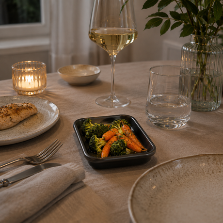 Liten ovnsform med grønnsaker, servise og glass i et lyst norsk hjem.