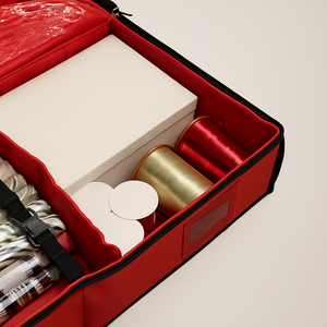 Detaljert visning av gavepapir, gavebånd og eske pent sortert i en rød oppbevaringsboks.