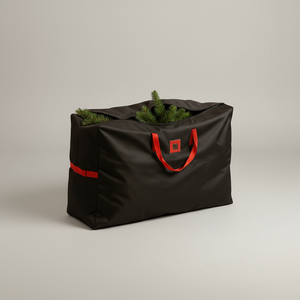 Svart oppbevaringsbag for juletre i solid stoff med røde detaljer, fotografert i naturlig kveldslys.