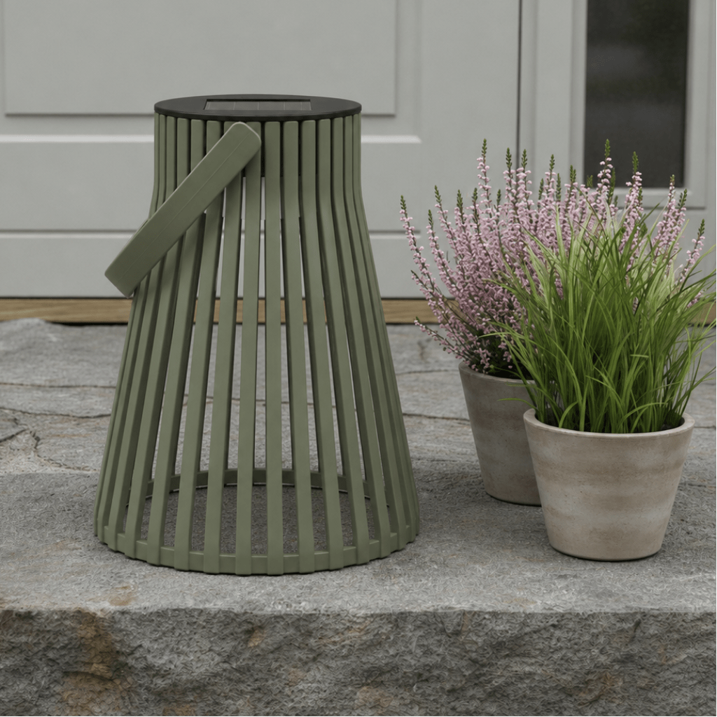 Grønn solarlykt plassert på en steinhelle ved et inngangsparti, med blomsterpotter i rosa og grønt ved siden av. - Lindas dekor 