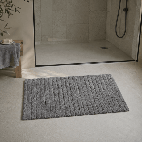 Grå Tiles baderomsmatte foran en dusj med glassvegg i et moderne baderom. - Lindas dekor