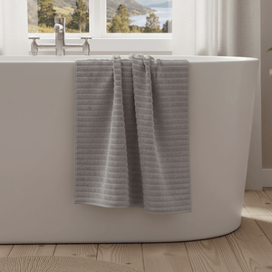Grått Inu badehåndkle hengende over badekarkant i lyst og moderne baderom.