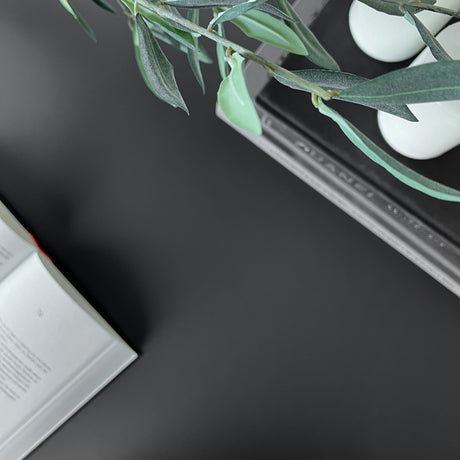 Detalj av sort selvklebende folie på hylle med dekor og sort lysestake