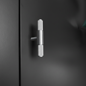 Kvadratisk bilde av Stockholm T-bar håndtak i sølv montert på sort skapdør