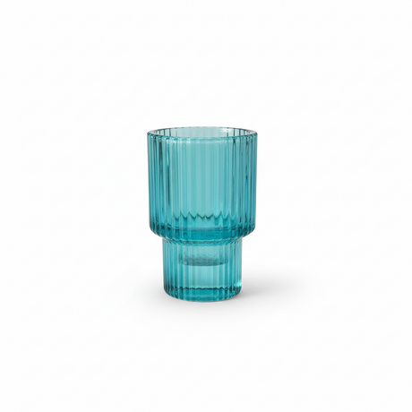 blå glass lysestake plassert på stuebord ved kopp og bok