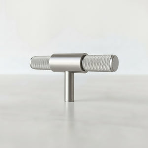 Kvadratisk bilde av minimalistisk T-bar håndtak i sølv på sort møbel