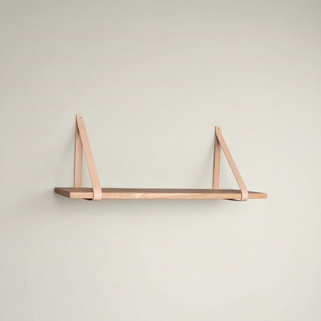 Forno vegghylle 120 cm i naturtre med brune skinnstropper montert på vegg