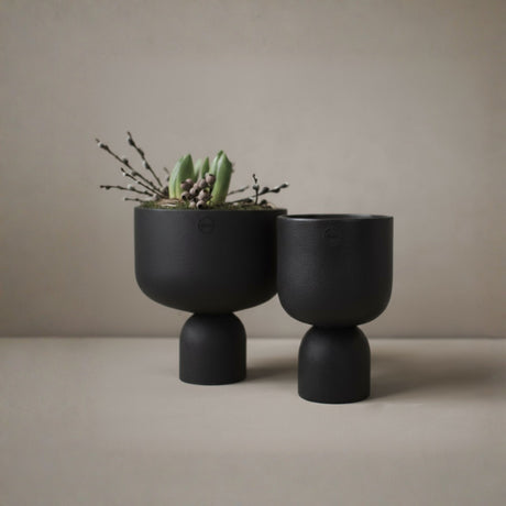 DBKD Post potte sort liten fra Lindas Dekor med grønn plante mot lys 