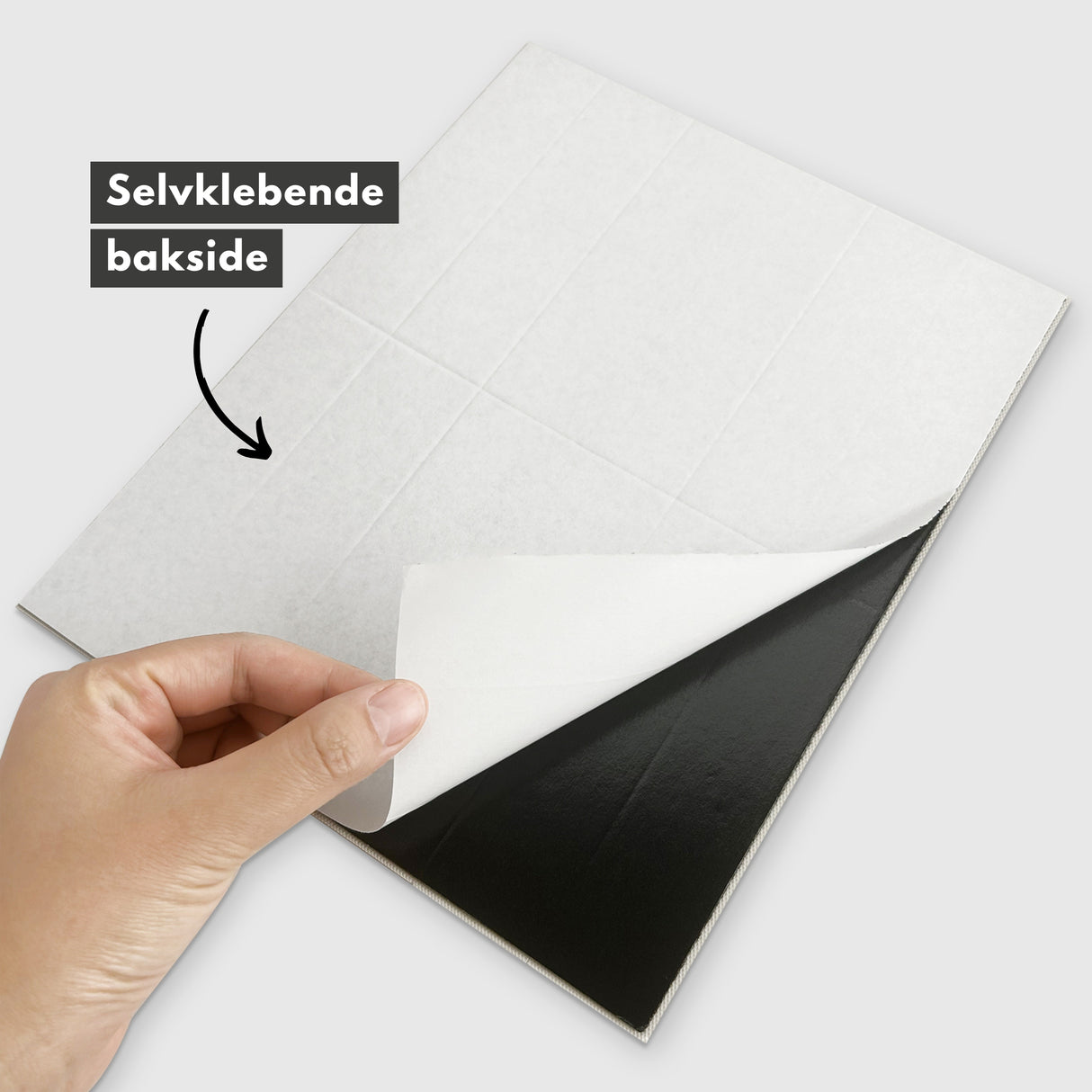 Hender som kutter Alma antrasitt marmorfliser med tapetkniv.