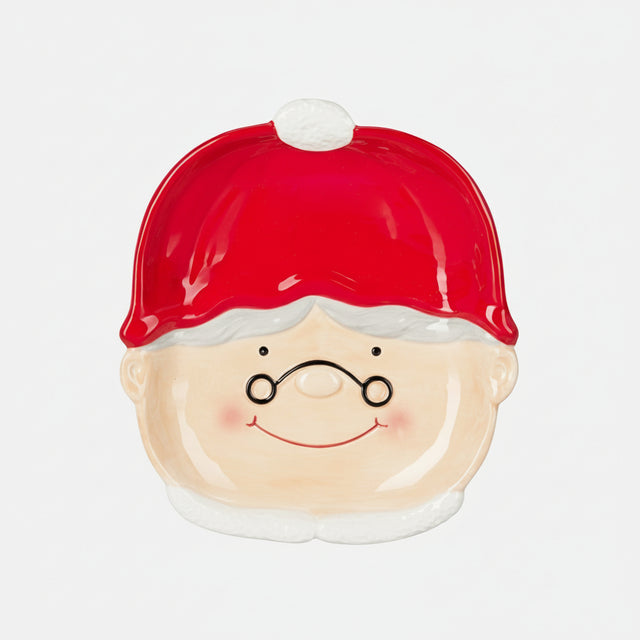 Dekorativ tallerken med nisseansikt på hvit duk med julepynt