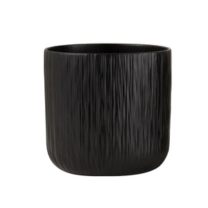 To sorte keramiske blomsterpotter, en glatt og en strukturert, på tregulv i moderne stueinteriør