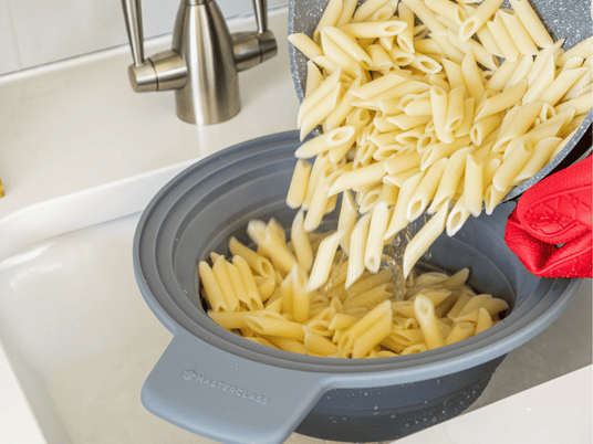 Grå MasterClass silikon silsats i hvit vask, nykokt pasta helles i og siles av