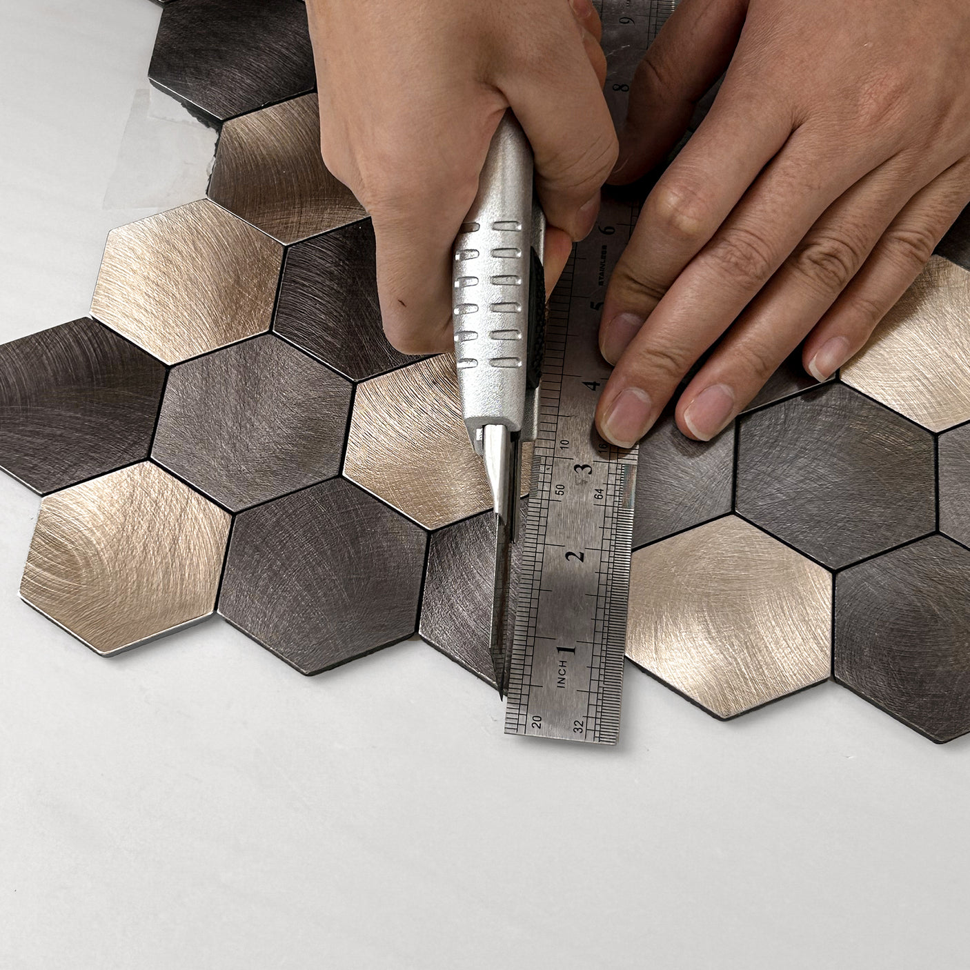 Hender som monterer latte hexagon selvklebende fliser på vegg.