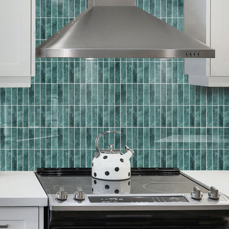 Grønne marmorfliser brukt som backsplash på kjøkken med hvite skap.