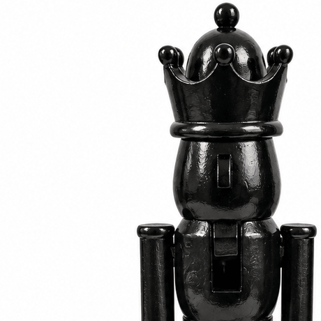 Nærbilde av svart nøtteknekkerfigur med blank overflate, dekorativ krone og detaljer i ansikt og uniform.