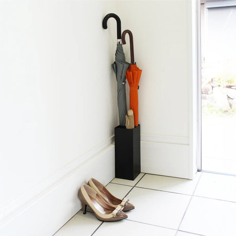 Sort paraplystativ i stål med plass til fire paraplyer i entré