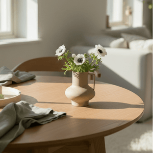 Dekorativ sandfarget vase med blomster på spisebord i lyst skandinavisk interiør