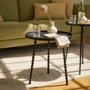 Runde svarte sidebord plassert ved sofa i nordisk stue