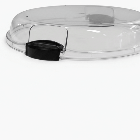 Transparent lock för en rund serveringsbräda med svarta handtag på sidorna. - Lindas dekor