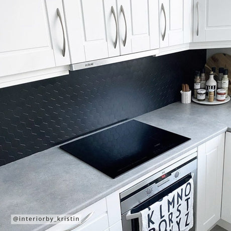 Kjøkkenbenk med dekor og flasker foran sort matt hexagon veggflis.