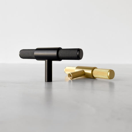 Elegant svart T-bar handtag med riftrad textur, perfekt för kök och badrum.